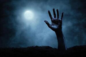 A decaying hand emerges from the earth beneath a full moon, creating an eerie and haunting scene photo