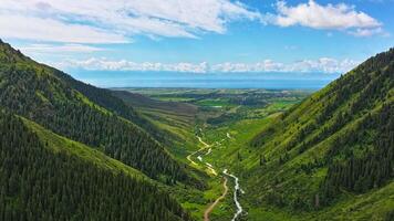 green mountains with white clouds on blue sky above, drone hyperlapse video
