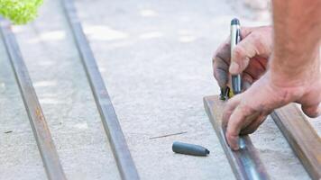 man marking square steel pipes with black chisel tip marker on concrete floor video