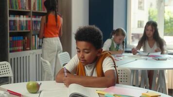 School library education class smiling African American happy little boy student pupil schoolboy learner child kid son portrait studying classmates children learn write homework draw read book lesson video