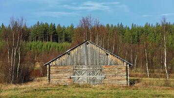Weathered barn standing alone amidst a peaceful, tree-lined countryside photo