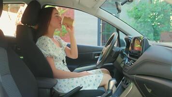 Happy satisfied Caucasian woman driver female client buyer owner girl drinking coffee cup touching car new automobile wheel enjoying morning routine going to work looking at camera smiling inside auto video