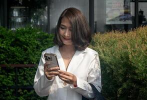 Businesswoman standing outdoor using smartphone send using texting message typing sms enjoying communication in mobile app photo