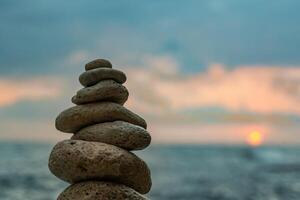 Rocks Stack Sunset Beach - A balanced stack of rocks stands against a beautiful sunset over a calm ocean. photo