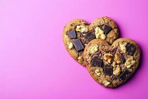 Heart shaped cookies with chocolate chunks and walnuts on pink background photo