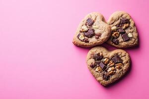 Heart-shaped cookies with chocolate and nuts on pink background photo