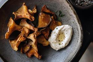 Delicious chanterelle mushrooms with creamy dip on a rustic plate photo