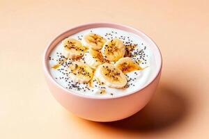 Banana slices and chia seeds on yogurt in a pink bowl against peach background photo