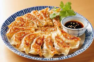 Crispy pan-fried gyoza dumplings with dipping sauce on decorative plate photo