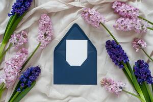 A wedding invitation mockup is displayed on a soft fabric surface, framed by vibrant spring flowers in various shades, creating a romantic atmosphere photo