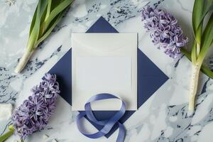 A beautifully arranged flat lay features a blank white wedding invitation on a marbled surface, accented by purple hyacinths and decorative ribbons, showcasing wedding elegance photo