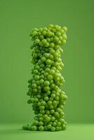 A tall cylindrical form made entirely of green grapes stands against a vibrant green background. The cluster showcases the fresh, glossy appearance of the grapes photo