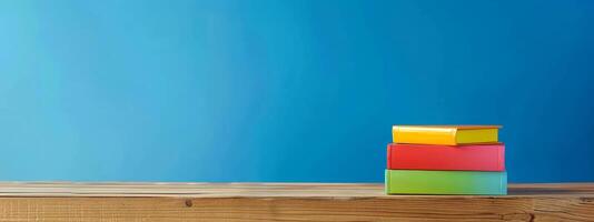 A stack of brightly colored books is arranged neatly on a rustic wooden table, adding vibrancy to the space and inviting a sense of curiosity and creativity photo