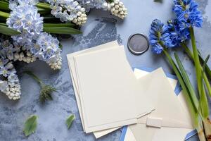 Delicate wedding invitation cards are artistically arranged with fresh blue flowers and greenery on a textured background, creating a serene and elegant atmosphere photo