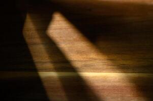Play of light and shadow on a wooden surface creates a warm, textured ambiance during the afternoon photo