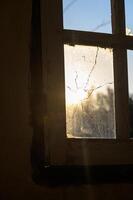 Sunrise breaks through a cracked window in an abandoned building photo