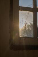 Sunlight filtering through a cracked window in an abandoned building at dusk photo