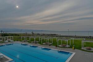 Calm evening by the seaside pool under a cloudy sky with distant mountains photo