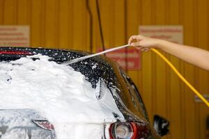 mano participación manguera aerosoles coche lavar espuma en el coche a limpiar y eliminar lodo, polvo, y varios manchas sin perjudicando el coche pintar y con un bonito oler. foto