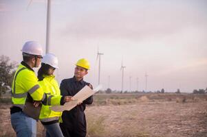 A team of maintenance engineers is planning the maintenance of wind turbines in a field. photo