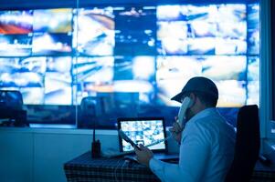 a man sitting at a desk with a laptop and a multiple monitors photo