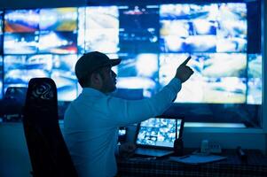 CCTV operator is pointing at multiple monitors photo