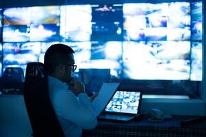 a man sitting at a desk in front of a large screen photo