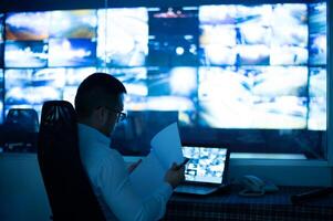 a man sitting at a desk with a laptop and a monitor photo