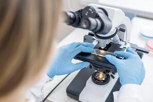 A person in a lab coat is looking at a microscope photo