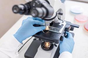 A person in a lab coat is using a microscope photo