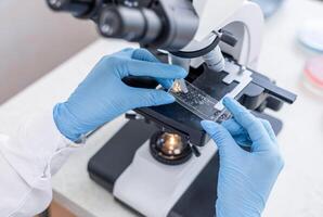 A person in a lab coat is using a microscope photo