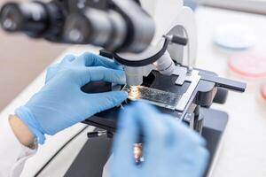 A person in a lab coat is using a microscope photo