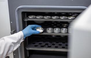 A person in a lab coat is holding a container photo