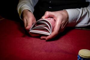 A man holding a stack of cards on a red table photo