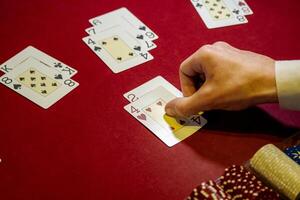 A person playing poker with cards on a red table photo