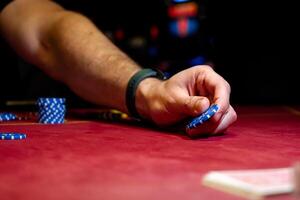 A man is holding a poker chip on a red table photo