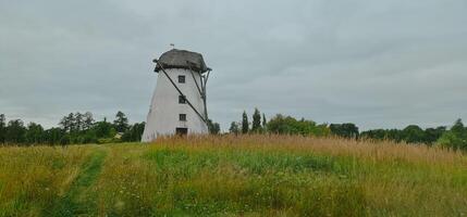 Old vintage white windmill in green field photo
