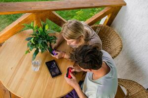 Man and woman watching a game console in a terrace in summer. Technology and game addiction concept photo