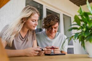 Man and woman watching a game console in a terrace in summer. Technology and game addiction concept photo