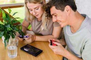 Joyful man and woman playing games on terrace. Technology and game console concept photo