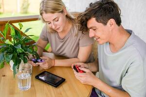 Man and woman watching a game console in a terrace in summer. Technology and game addiction concept photo