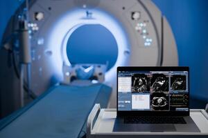 View of Laptop, computer with medical data interface screen in the middle of MRI, CT scanner. High-tech modern CT scan room, Health care and medical concept. Blue background. Free copy space photo
