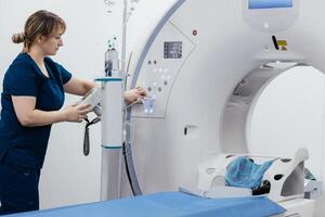 Medical nurse, doctor push buttons of a modern CT scanner while attending to a patient in a medical facility. The scene highlights advanced technology and healthcare support for diagnostic imaging photo