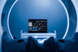 View of Laptop, computer with medical data interface screen in the middle of MRI, CT scanner. High-tech modern CT scan room, Health care and medical concept. Blue background. Interior Of Radiography photo
