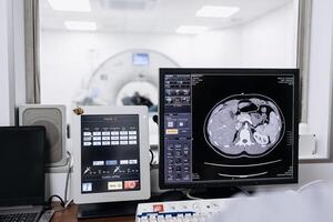 Doctor examining X-ray images on display in MRI control room while in background nurse preparing the patient for examination test photo