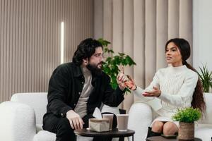Couple fighting arguing problems about relationship while sitting on couch at home. Angry girlfriend discussing issues with boyfriend reacting with frustration. photo
