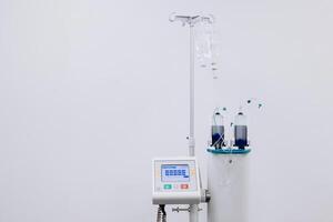 A drip with saline solution in the operating room. Syringe pump with medical equipment background. Intravenous fluid infusion for patient with blood loss during surgery. Isolated on white. Copy space photo