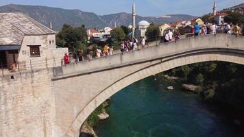 Tourists on the famous old arch bridge in Mostar. Close-up view of the summer tourist attraction of the famous bridge symbol of the city video