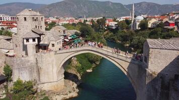 Tourists on the famous old arch bridge in Mostar. Aerial view of the summer tourist attraction of the famous bridge symbol of the city video