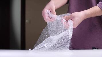 Man popping bubbles in bubble wrap on white table video